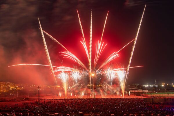 A vibrant fireworks show lights up the night sky over a bustling city gathering.