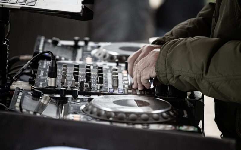DJ mixing music on a professional sound mixer during an outdoor performance.